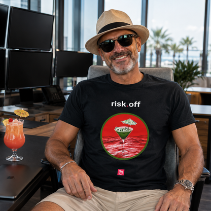 Black risk.off nano.narrative tee worn by a relaxed experienced trader in a bright institutional trading office, smiling at the camera while wearing a vacation hat beside a tropical cocktail and powered-down trading screens.